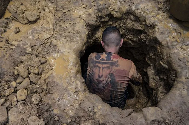 A Venezuelan miner wearing a shirt with the image of “Uncle Sam” works digging in a mine to extract gold, which will then be sold in El Callao, Bolivar State, Venezuela, on August 29, 2023. In the town of El Callao, extracting gold from soil starts off as a kid's game, but soon becomes a full-time job that human rights activists says amounts to child exploitation. (Photo by Magda Gibelli/AFP Photo)