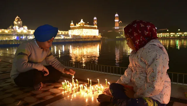 Young Sikhs light candles at the illuminated Golden Temple, Sikhs holiest shrine, early morning to mark the birth anniversary of Guru Nanak, the first Sikh Guru and the founder of Sikhism, in Amritsar, India, Monday, November 27, 2023. (Photo by Prabhjot Gill/AP Photo)