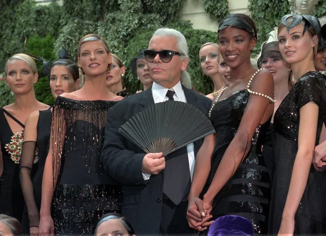 In this Tuesday July 9, 1996 file photo, Karl Lagerfeld is surrounded by Canadian model Linda Evangelista, left, and British model Naomi Campbell, right, and other models after the presentation of his 1996-97 fall-winter haute couture fashion collection for Chanel in Paris. Chanel's iconic couturier, Karl Lagerfeld, whose accomplished designs as well as trademark white ponytail, high starched collars and dark enigmatic glasses dominated high fashion for the last 50 years, has died. He was around 85 years old. (Photo by Lionel Cironneau,/AP Photo)