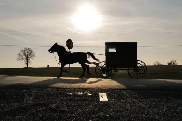 An Amish buggy passes on the road at sunset in Strasburg, Pennsylvania on January 3, 2023. (Photo by Charly Triballeau/AFP Photo)