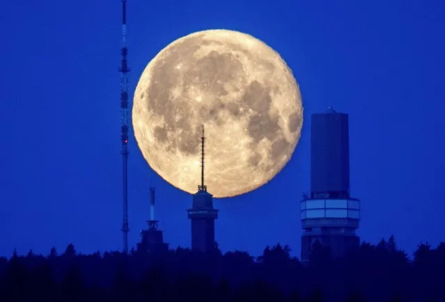 The moon sets behind buildings on top of the Feldberg mountain near Frankfurt, Germany, early Monday, June 5, 2023. (Photo by Michael Probst/AP Photo)
