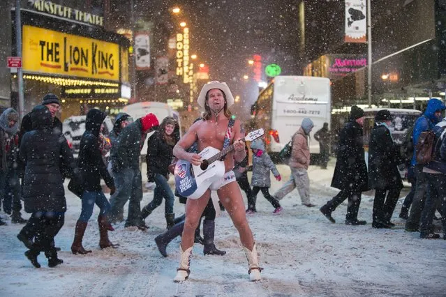 Robert Burck (L), also known as the original “Naked Cowboy”, performs in a snow storm on the streets of Times Square, New York January 21, 2014. (Photo by Darren Ornitz/Reuters)