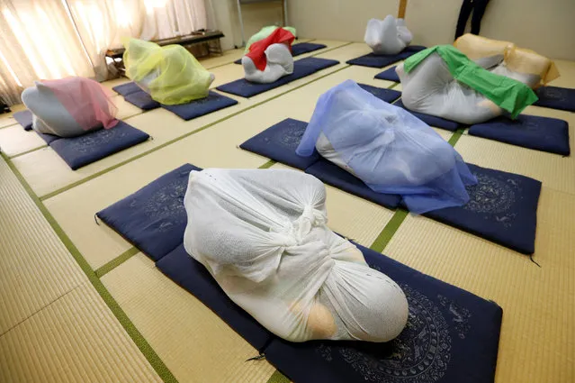 Participants perform Otonamaki, which translates as “adult wrapping”, a new form of therapy where people are wrapped in large swaddling cloth to alleviate posture problems and stiffness, at a session in Asaka, Saitama prefecture, Japan, February 4, 2017. (Photo by Toru Hanai/Reuters)