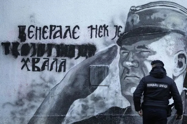 A police officer walks by a mural of former Bosnian Serb military chief Ratko Mladic in Belgrade, Serbia, Tuesday, November 9, 2021. Police officers were deployed Tuesday at the site of a large wall painting in Belgrade of convicted Bosnian Serb wartime commander Ratko Mladic which rights activists wanted to remove. The gathering, which was to coincide with the international day of anti-Fascism and anti-Semitism, was banned by the police which said that they were preventing possible clashes between the activists and the right-wing nationalists who consider the Serb general a hero. (Photo by Darko Vojinovic/AP Photo)