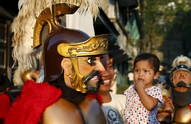 A girl looks at a penitent wearing a “Morions” mask during a religious procession as part of Holy Week celebrations at Boac, Marinduque in central Philippines March 23, 2016. (Photo by Erik De Castro/Reuters)