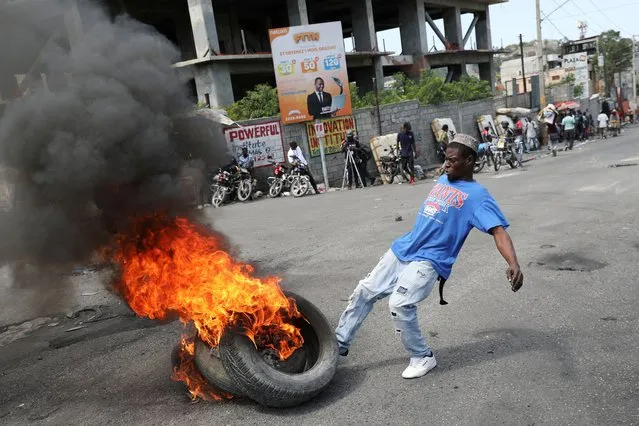 A man kicks burning tires during a protest as the government said it would extend a state of emergency for another month after an escalation in violence from gangs seeking to oust the Prime Minister Ariel Henry, in Port-au-Prince, Haiti, on March 7, 2024. (Photo by Ralph Tedy Erol/Reuters)