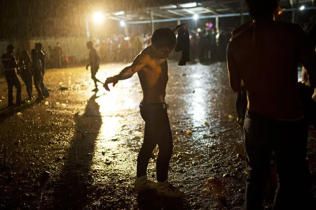 In this March 16, 2015 photo, a young man dances under a heavy rain during a concert by huayno singer Ely Corazon, in La Mar, province of Ayacucho, Peru. The average cocaine backpacker, or mochilero, is typically recruited by relatives and friends – often at festivities where liquor flows. They tend not to tell their parents, who nearly always disapprove. (Photo by Rodrigo Abd/AP Photo)