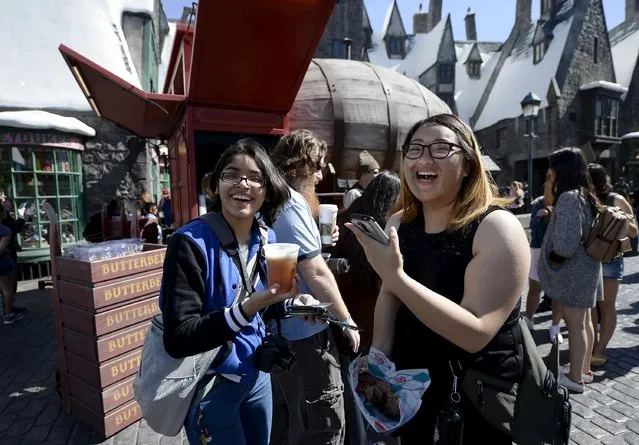 Guests try out Butterbeer served from a large barrel shaped Butterbeer cart in Hogsmeade Village during a soft opening and media tour of “The Wizarding World of Harry Potter” theme park at the Universal Studios Hollywood in Los Angeles, California in this picture taken March 22, 2016. (Photo by Kevork Djansezian/Reuters)