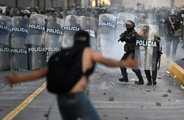Demonstrators clash with riot police during a protest against the government of Dina Boluarte asking for her resignation and the closure of Congress, in Lima on January 24, 2023. Peru's President Dina Boluarte called for a “national truce” as thousands of protesters continue to call for her resignation and fresh elections, following weeks of protests that have at times turned violent, with at least 46 people killed in clashes between demonstrators and security forces. (Photo by Ernesto Benavides/AFP Photo)