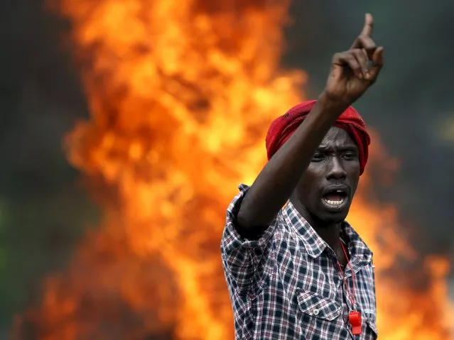 A protester gestures in front of a burning barricade during a protest against Burundi President Pierre Nkurunziza and his bid for a third term in Bujumbura, Burundi, May 21, 2015. (Photo by Goran Tomasevic/Reuters)