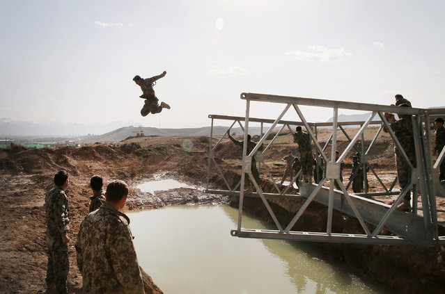 A soldier with the Afghan National Army's (ANA) National Engineer Brigade tries to make dry land after leaping from the top of a Mabey-Johnson portable pre-fabricated bridge which his unit was learning to construct with the help of U.S. Navy Seabees from Naval Mobile Construction Battalion (MCB) 28 at the ANA's combined Fielding Center on March 18, 2014 in Kabul, Afghanistan. The Seabees are attached to the U.S. Army's 130th Engineer Brigade are responsible for training ANA soldiers various engineering tasks at the facility. (Photo by Scott Olson/Getty Images)