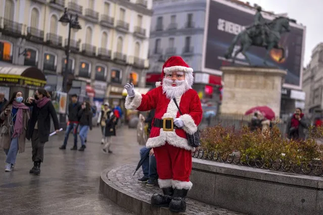 A man dressed as Santa Claus gestures at Sol square in downtown Madrid, Spain, Friday, December 24, 2021. The Spanish government has ordered mandatory mask-wearing outdoors, with few exceptions, starting from Friday. (Photo by Manu Fernandez/AP Photo)