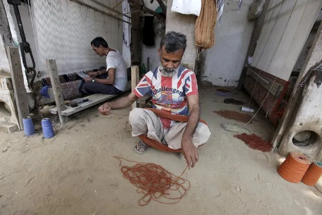 A traditional carpet weaver sorts wool yarn before weaving on a handmade loom in a workshop on the outskirts of Karachi, Pakistan April 11, 2016. (Photo by Akhtar Soomro/Reuters)