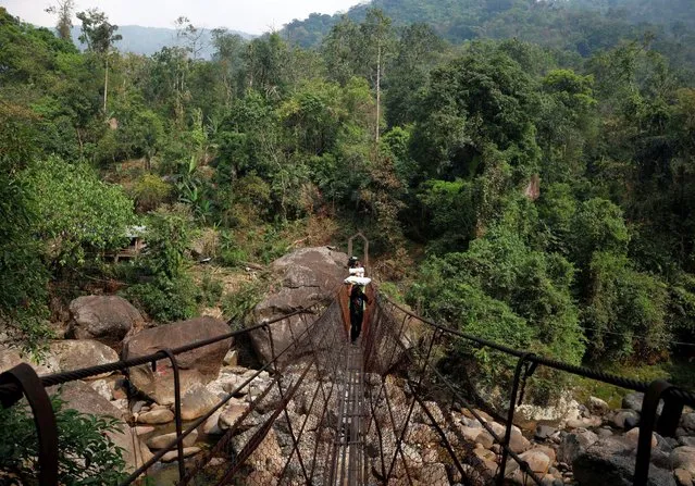 Cornelius Mawa, 28, a porter, carries Voter Verifiable Paper Audit Trail (VVPAT) and Electronic Voting Machines (EVM) as he crosses a suspension bridge to reach a remote polling station, ahead of the first phase of the election, in Shillong in the northeastern state of Meghalaya, India, April 17, 2024. (Photo by Adnan Abidi/Reuters)
