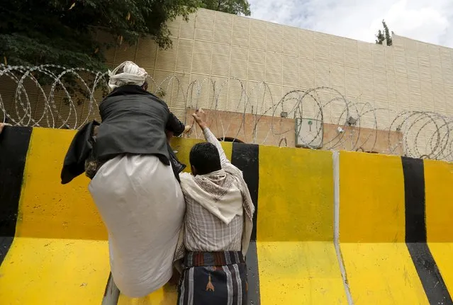 Houthi followers climb a barricade outside the Saudi embassy as they prepare to hang a banner against Saudi-led air strikes, in Sanaa May 25, 2015. (Photo by Khaled Abdullah/Reuters)