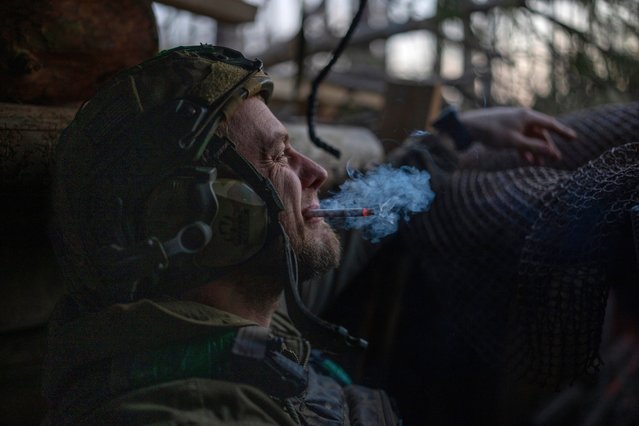 A Ukrainian serviceman from the Azov brigade, known by the call sign Chaos, smokes a cigarette while he waits for a command to fire, in a dugout around one kilometer away from Russian forces on the frontline in Kreminna direction, Donetsk region, Ukraine, Friday, April 12, 2024. (Photo by Alex Babenko/AP Photo)