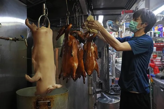 A staff member in the kitchen takes out a roasted goose from the oven and hangs on the rack to drip oil while making the “Poon Choi” dish at the RenRen Heping Restaurant in Hong Kong on Jan. 21, 2022. Tighter COVID-19 restrictions, including a ban on dining in restaurants after 6 p.m., are making Hong Kong residents plan their annual reunion dinner on Lunar New Year’s eve at home. (Photo by Kin Cheung/AP Photo)