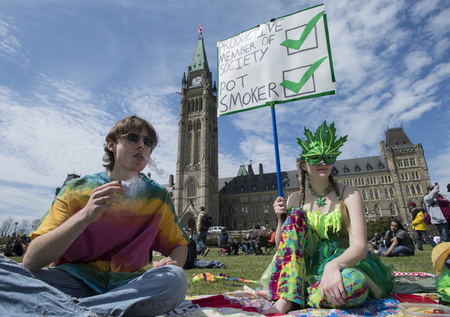 People gather on the lawns of Parliament Hill during the Fill the Hill marijuana rally on Parliament Hill in Ottawa on Sunday, April 20, 2014. (Photo by Justin Tang/The Canadian Press)