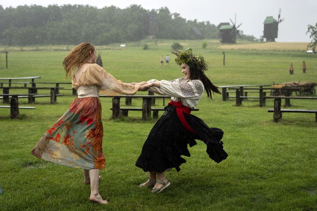 Ukrainian young women dressed in traditional clothing dance under heavy rain at a traditional Midsummer Night celebration near capital Kyiv, Ukraine, Sunday, June 23, 2024. The age-old pagan festival is still celebrated in Ukraine amid the third year of Russia-Ukraine war. (Photo by Efrem Lukatsky/AP Photo)