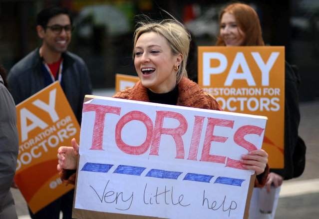 People hold placards calling for better pay, on a picket line outside the Royal London Hospital in east London on April 12, 2023, on the second day of a strike by junior doctors – physicians who are not senior specialists but who may still years of experience. Doctors working in England's public health service on Tuesday launched what has been billed as the most disruptive strike in its history, in a dispute over pay and working conditions. (Photo by Daniel Leal/AFP Photo)