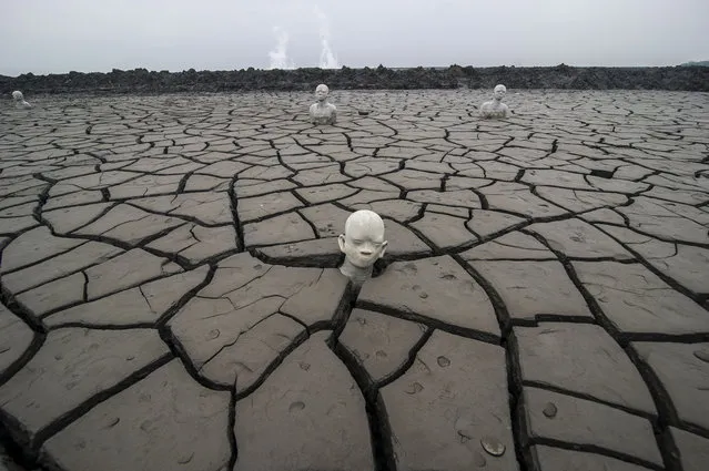 This picture taken on May 29, 2017 shows statues standing semi-submerged in mud, a symbol of the human toll of the 2006 disaster, at the mud volcano incident area in Sidoarjo, East Java. A mud volcano that erupted in central Indonesia a decade ago and swallowed entire villages is still oozing its all-consuming sludge, but for some entrepreneurial locals it has provided an unlikely business opportunity. “Mud tourism” is booming, as visitors flock to see rooftops poking above the giant bubbling lake, life-size statues made of mud and haunting memorials to one of the countrys worst environmental disasters. (Photo by Juni Kriswanto/AFP Photo)