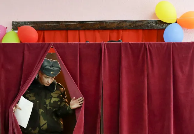 In this photo taken on Thursday, November 14, 2019, a Belarus' Army serviceman walks to cast his ballot during an early election at a polling station in Minsk, Belarus, ahead of the parliamentary election to be held on Sunday. (Photo by Sergei Grits/AP Photo)
