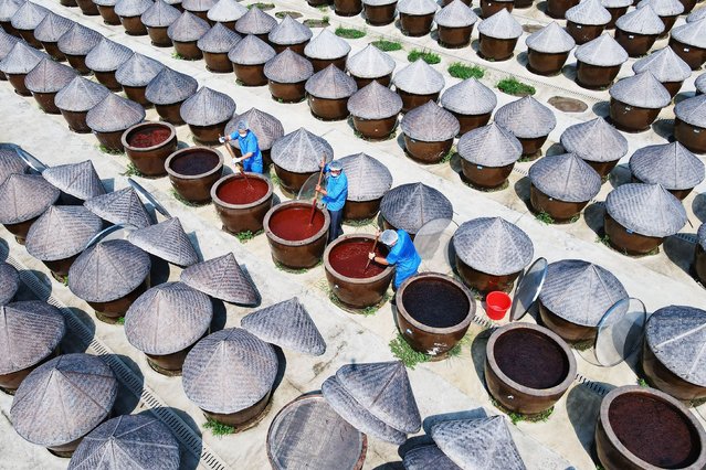 Workers use a wooden rake to turn sauces at the old soy sauce natural drying sauce shop in Yanhe Village, Rucheng Street, Rugao city, East China's Jiangsu province, on August 22, 2024. (Photo by Costfoto/NurPhoto/Rex Features/Shutterstock)