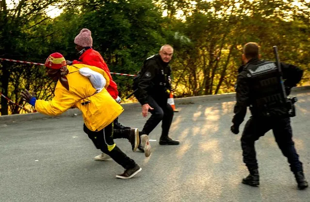 French gendarmes attempt to block migrants after they entered the Eurotunnel site in Coquelles near Calais, northern France, on July 30, 2015. French authorities said on July 30 that a migrant had died from head injuries suffered in a weekend attempt to cross the Channel into England, bringing the number of such deaths to 10 since June. Every night, hundreds of migrants make desperate attempts to enter the Eurotunnel premises in order to get to Britain, seen as an Eldorado. (Photo by Philippe Huguen/AFP Photo)