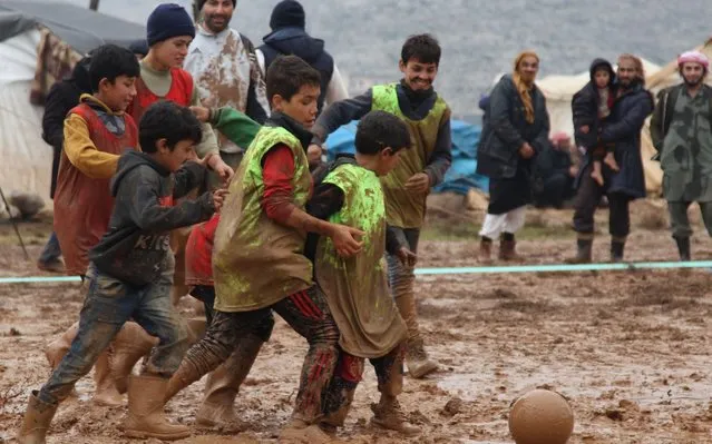 Syrians play a game of football organized by local activists in a muddy field in a camp for the internally displaced west of Sarmada town in Syria's northwestern province of Idlib, on January 2, 2020. The latest round of violence in Syria's nearly nine-year-old war, saw regime forces upping their deadly bombardment of the northwestern province of Idlib, pushing, in December alone according to the United Nations, some 284,000 from their homes in the jihadist-run region of some three million people. (Photo by Abdulaziz Ketaz/AFP Photo)