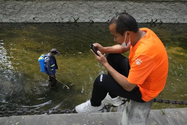 A worker wearing a mask disinfects a canal on Thursday, May 19, 2022, in Beijing. (Photo by Ng Han Guan/AP Photo)