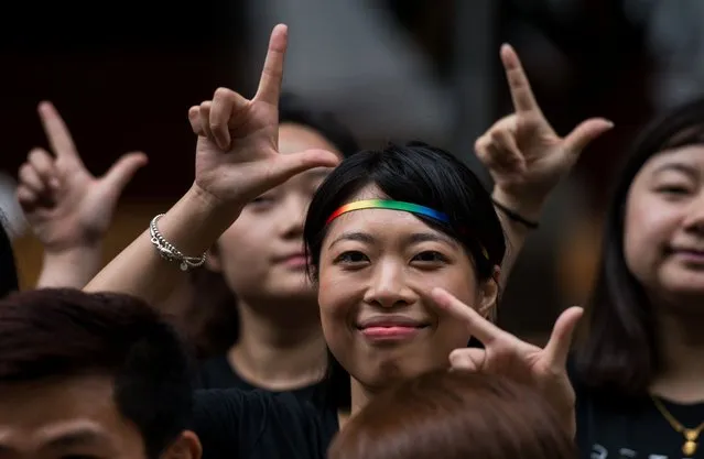 Runners of the Shanghai Pride Run make signs with their fingers while wearing rainbow shoelaces at the start of the race in Shanghai on June 18, 2016. The LGBT festival, Shanghai PRIDE 2016, which celebrates diversity in the Chinese city under this year's theme “I Am Me”, kicked-off with a fun run and will last from June 17 to 26. (Photo by Johannes Eisele/AFP Photo)