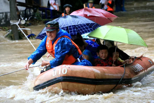 A rescuer grabs a rope to prevent a raft carrying residents from being flushed away as residents are evacuated from a flooded area in Jiujiang, Jiangxi Province, China, June 19, 2016. (Photo by Reuters/Stringer)