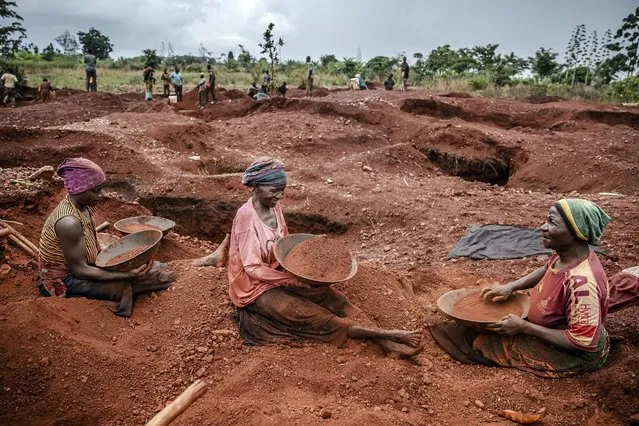 Tanzanian miners Mwagyma Ramadhan, Regina Daud and Maria Ng'ombe look for gold at an open-pit gold mine in Nyarugusu, Geita Region, Tanzania on May 27, 2022. Tanzania is a land rich in minerals and one of the main gold producers in Africa, with gold representing more than 90% of the country's mineral exports. Artisanal and small-scale gold mining have culturally and historically relegated women's participation. The extractive sector in Tanzania has historically been a male-dominated industry with high levels of harassment, sexual abuse, discrimination and misconceptions over women's involvement, and contributions following traditional beliefs. A a result women face economic challenges due to lack of access to the land. Through the creation only-women miners associations and the help of projects advocating for rights and inclusion in the extractive industry such as the Collective Action For Rights Realisation In Extractives Industry (CLARITY), Tanzanian women in Geita region have been gradually gaining access to the mines while being able to benefit from the sector. (Photo by Luis Tato/AFP Photo)