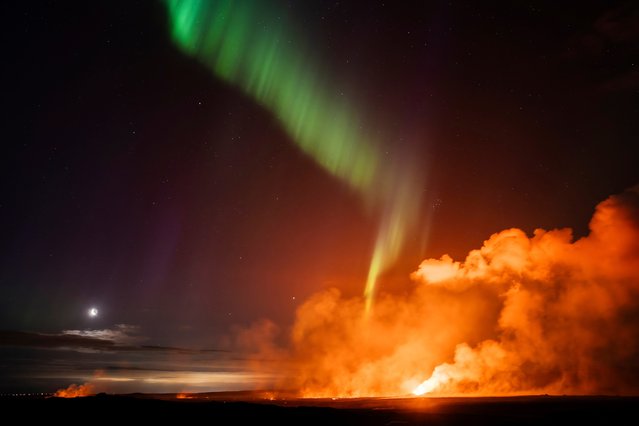 The northern lights appear above the eruption site with the moon on the Reykjanes Peninsula, in Iceland, Thursday, August 29, 2024. (Photo by Marco di Marco/AP Photo)