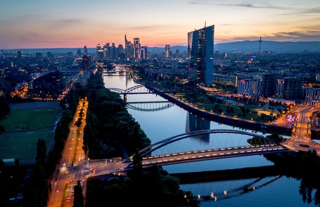 The sun sets over buildings of the banking district and the river Main in Frankfurt, Germany, Sunday, July 28, 2024. (AP Photo/Michael Probst)