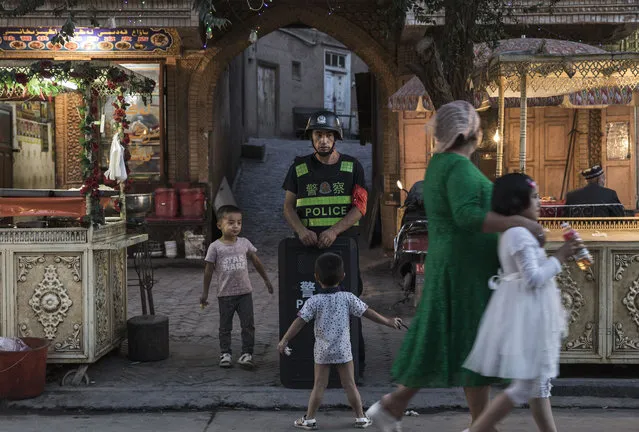 Ethnic Uyghur children joke as they taunt a local police officer on June 29, 2017 in the old town of Kashgar, in the far western Xinjiang province, China. (Photo by Kevin Frayer/Getty Images)