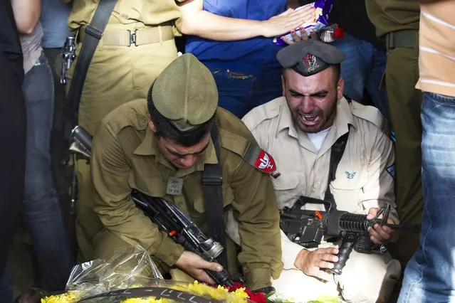 Israeli soldiers mourn next to the grave of Israeli soldier Daniel Kedmi during his funeral in Tel Aviv July 29, 2014. Israel knocked out Gaza's only power plant, flattened the home of its Islamist Hamas political leader and pounded dozens of other high-profile targets in the enclave on Tuesday, with no end in sight to more than three weeks of conflict. (Photo by Ronen Zvulun/Reuters)