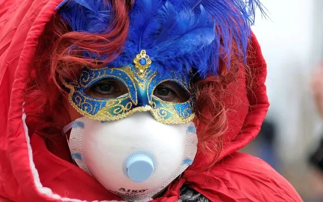 Masked carnival reveller wears protective face mask at Venice Carnival, which the last two days of, as well as Sunday night's festivities, have been cancelled because of an outbreak of coronavirus, in Venice, Italy on February 23, 2020. (Photo by Manuel Silvestri/Reuters)