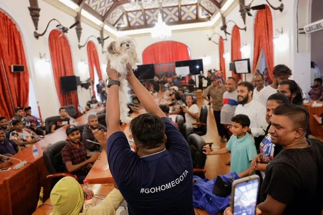 A demonstrator shows a dog as the new “Wildlife Minister” at the President Gotabaya Rajapaksa's cabinet meeting room, at the President's house, on the following day after demonstrators entered the building, after President Gotabaya Rajapaksa fled, amid the country's economic crisis, in Colombo, Sri Lanka on July 10, 2022. (Photo by Dinuka Liyanawatte/Reuters)