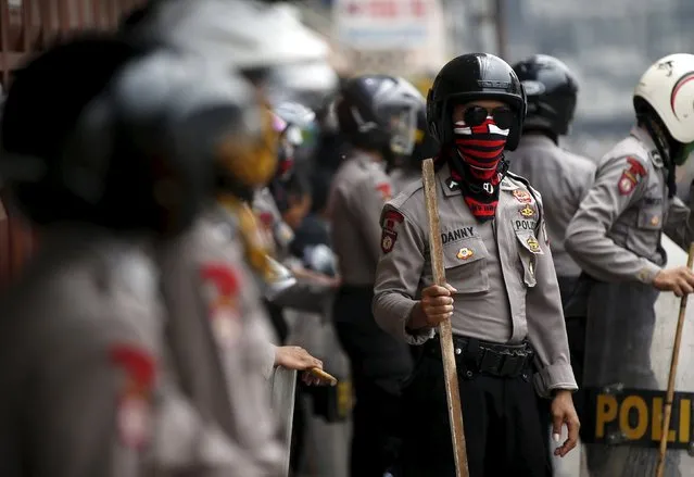 Indonesian policemen stand guard on a street after clashing with residents at Kampung Pulo district in Jakarta, August 20, 2015. (Photo by Darren Whiteside/Reuters)