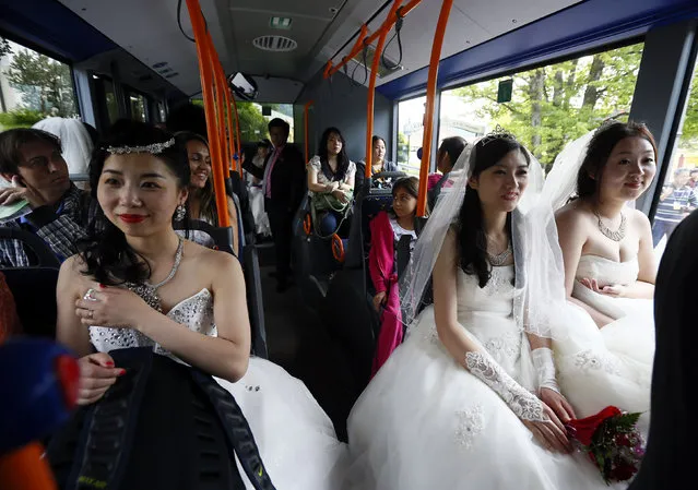 Chinese bridal couples travel on a public bus to the Neuschwanstein castle after their symbolic wedding in Fuessen May 31, 2012. Some 15 Chinese couples who already married in China, travelled to Germany to repeat their promise of marriage at Neuschwanstein Castle, one of the most popular destinations in Europe. (Photo by Michael Dalder/Reuters)
