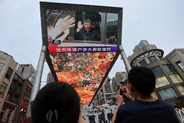 A giant screen shows news footage of Chinese President Xi Jinping visiting Xinjiang Uyghur Autonomous Region, at a shopping centre, in Beijing, China, July 15, 2022. (Photo by Tingshu Wang/Reuters)