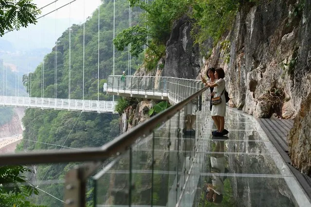 Visitors stand on the walkway section of the Bach Long glass bridge in Moc Chau district in Vietnam's Son La province on April 29, 2022. Vietnam launched a new attraction for tourists – with a head for heights – on April 29 with the opening of a glass-bottomed bridge suspended some 150 metres above a lush, jungle-clad gorge. (Photo by Nhac Nguyen/AFP Photo)