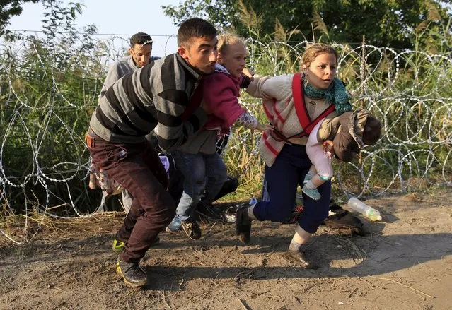 Syrian migrants run after crossing under a fence as they enter Hungary, at the border with Serbia, near Roszke, August 27, 2015. (Photo by Bernadett Szabo/Reuters)