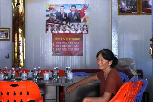 A woman rests near a poster showing Chinese leaders including Chinese President Xi Jinping and Chinese Premier Li Keqiang in Pingtan in eastern China's Fujian province, Saturday, August 6, 2022. Taiwan said Saturday that China's military drills appear to simulate an attack on the self-ruled island, after multiple Chinese warships and aircraft crossed the median line of the Taiwan Strait following U.S. House Speaker Nancy Pelosi's visit to Taipei that infuriated Beijing. (Photo by Ng Han Guan/AP Photo)