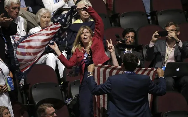 Supporters of Republican U.S. presidential nominee Donald Trump obscure a protester from the activist group Code Pink holding an anti-racism and anti-hate banner, so that only her hand (R) making a peace sign can be seen as she interrupts the proceedings at the Republican National Convention in Cleveland, Ohio, U.S. July 19, 2016. (Photo by Mike Segar/Reuters)