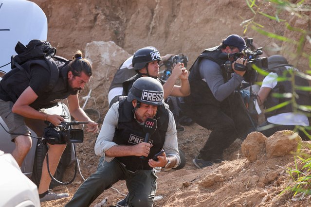 Reporters take cover upon hearing sirens warning of an incoming rocket attack from Gaza, in the southern Israeli city of Sderot, on October 23, 2023, amid ongoing battles between Israel and the Palestinian group Hamas. (Photo by Jack Guez/AFP Photo)
