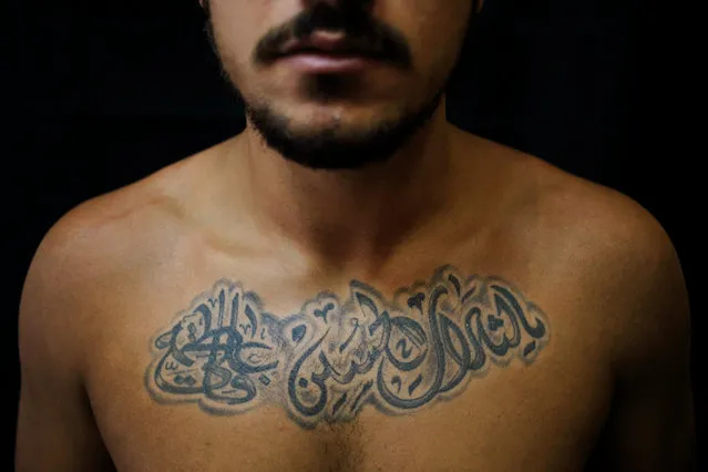 In this Monday, July 18, 2016 photo, Alodi Issa, 22, poses for a photo showing off his tattoos with Shiite Muslim religious slogans in the southern suburb of Beirut, Lebanon. The tattoo in Arabic reads, “Oh, the revenge for Hussein. Ali, Fatima”. (Photo by Hassan Ammar/AP Photo)