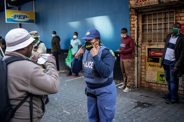 A South African Police Service (SAPS) officer commands a man to wear a face mask in Hillbrow, Johannesburg, on May 1, 2020, during a joint patrol by the South African National Defence Force (SANDF), the South African Police Service (SAPS) and the Johannesburg Metro Police Department (JMPD). South Africa began to gradually loosen its strict COVID-19 coronavirus lockdown on May 1, 2020, after five weeks of restrictions. (Photo by Michele Spatari/AFP Photo)