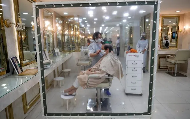 A customer receives haircut by a Thai hairdresser wearing protective suit and face shield next to plastic shield set up to prevent the COVID-19 after the government allows beauty salon services as part of the easing some stringent measures to combat the slowdown of COVID-19 coronavirus pandemic, at a beauty salon in Bangkok, Thailand, 04 May 2020. The Thai government announced to restart some businesses, a raft of shop and services as well as some activities with social distancing and restriction guidelines as part of the easing some stringent measures imposed to curb the ongoing COVID-19 coronavirus pandemic after the number of deadly disease infections in Thailand has been dropped while the state of emergency decree and curfew will remain for another month until the end of May. (Photo by Rungroj Yongrit/EPA/EFE/Rex Features/Shutterstock)